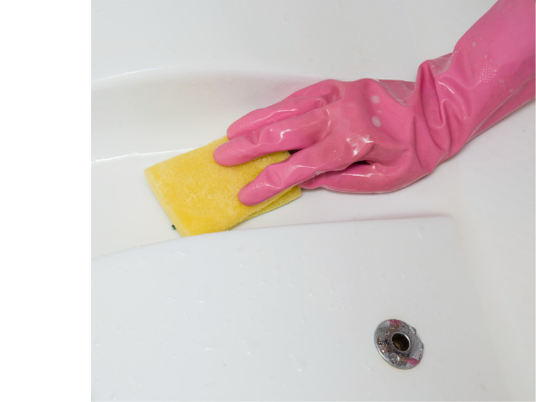 Hand in pink glove wiping down hot tub surface with a yellow rag