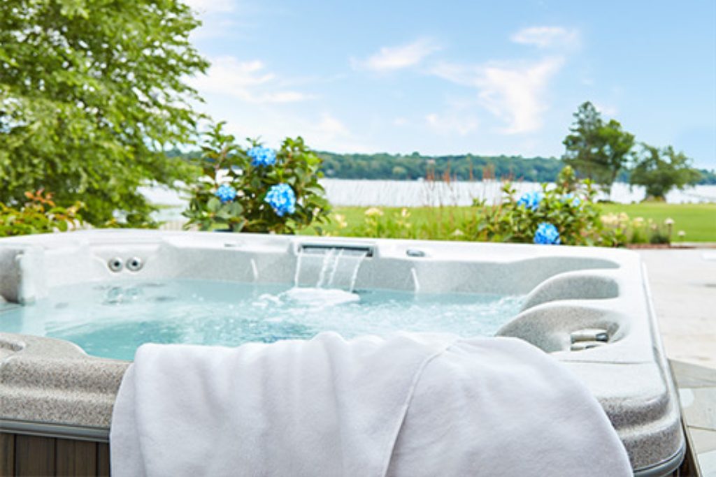 Image of an outdoor hot tub with a white towel sitting on the edge of the hot tub.