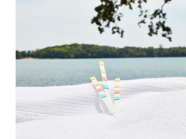 3 colored test strips sitting on a white towel in front of a lake