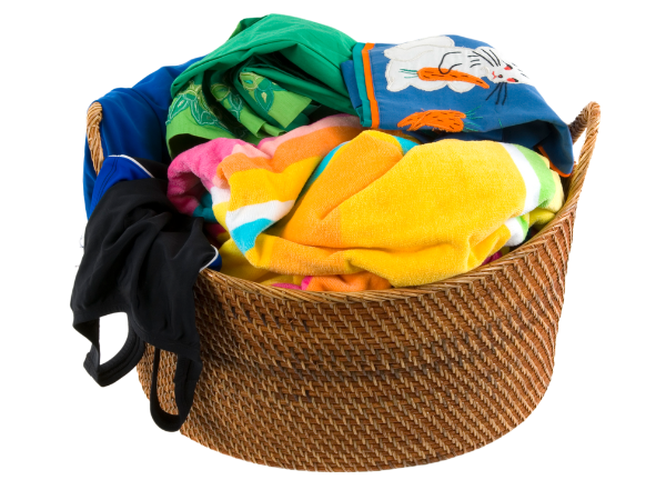 Brown wicker basket filled with laundry, including bright-colored towels and swimsuits.