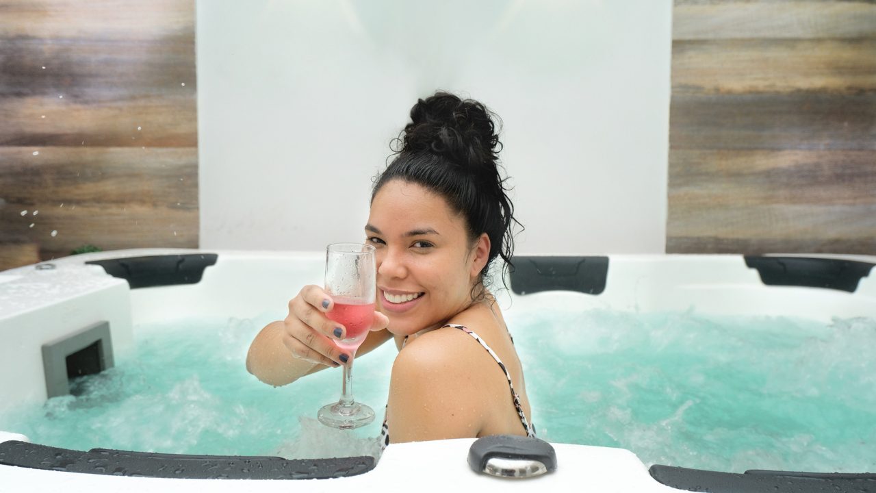 Woman in spa turned to the back and looking at the camera as she cheers her champagne glass