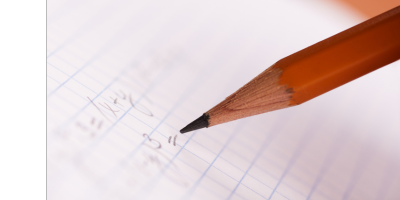 A red pencil jots down math equations on college ruled paper