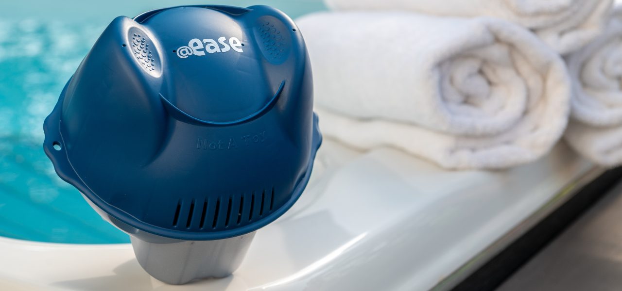 A photo of FROG @ease for Swim Spas that sits on a swim spas edge next to 3 rolled up white towels