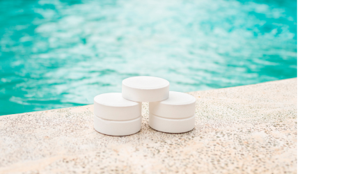 A shot of a pool edge with 3 chlorine pucks stacked in a pyramid.