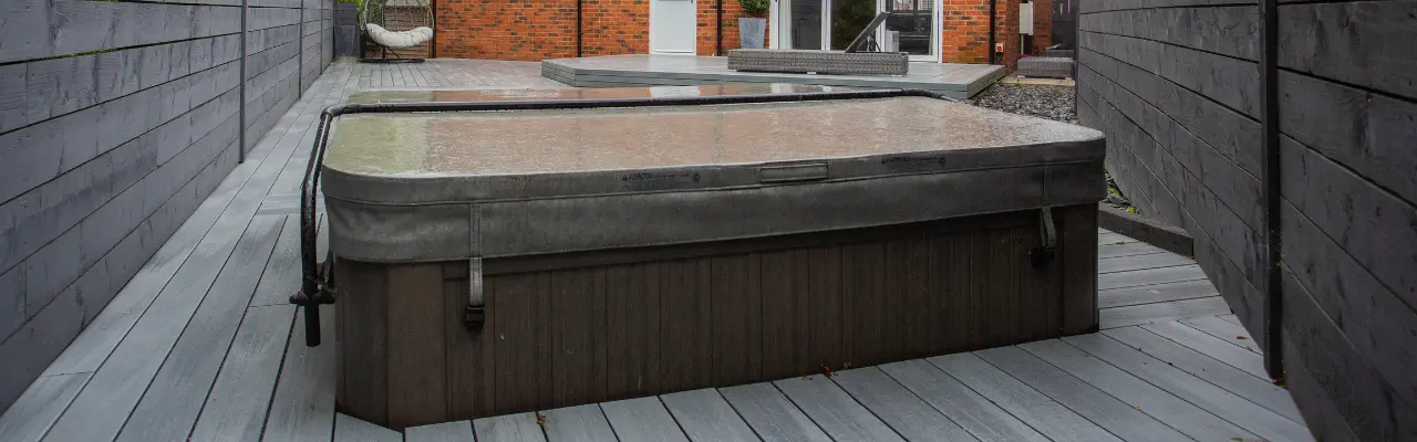 A hot tub with its cover on in the backyard of a red brick house