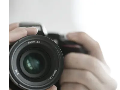 A closeup shot of hands taking a photo on a black camera.