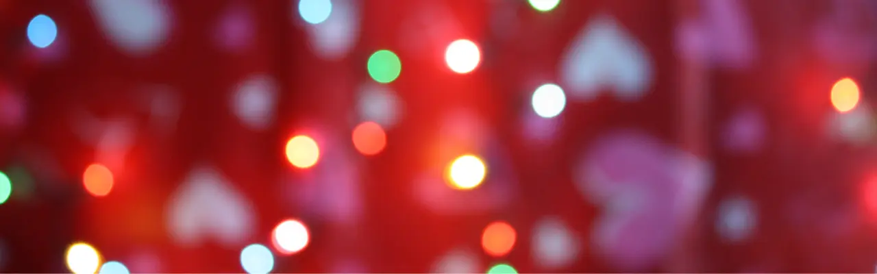 A closeup image of Valentine's Day festive lights in red, pink and white. Some of the lights are heart-shaped.