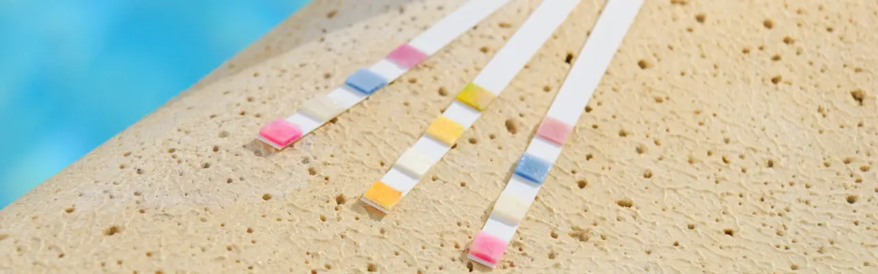 Three used test strips sit on the pool's edge.